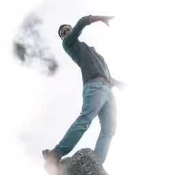 the man is standing on top of a rock and is smoking