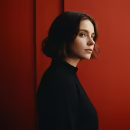 a woman with dark hair and black top looking out the window