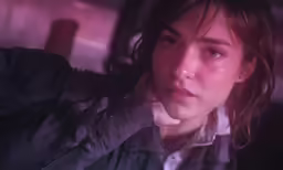 a girl standing in a dark room wearing a grey shirt