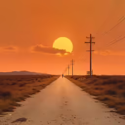 an empty dirt road in front of the sun
