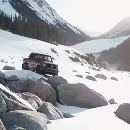 a red jeep driving on top of a snowy hill