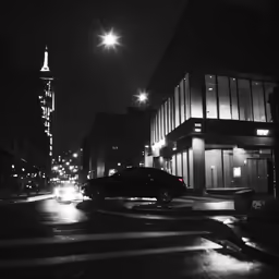 cars on a city street at night with lights shining in the background