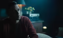 a man in a dark room looking off to his left