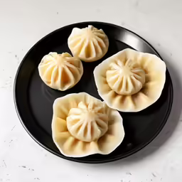 three dumplings in black plate with white background