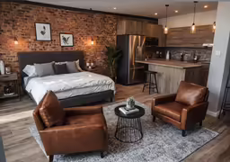 there is a bed, two chairs, table and an island in the middle of this room