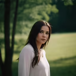 a beautiful young woman posing for a picture in front of a tree