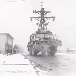 a military vehicle in the snow near some buildings