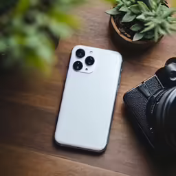 a phone on a wooden table next to a camera