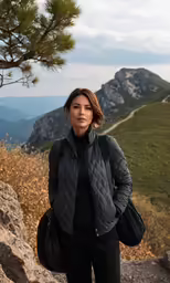 a beautiful young woman standing on top of a mountain