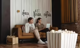 couple sitting on a couch looking at movie ticket