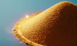 a small candle shines in the center of a mound of sand
