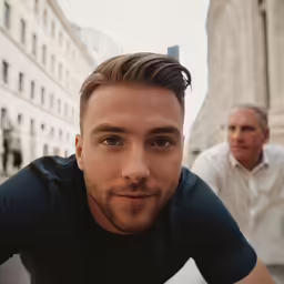 a young man looks on as a younger gentleman rests against the building