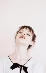 a young woman with her eyes closed wearing a black bow tie