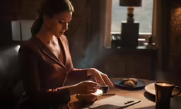 woman is working at table with tea and cookies