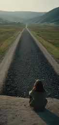 there is a woman sitting on the edge of a road