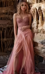 a woman is wearing a pink dress and a high slit
