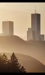 the view of two large concrete buildings from atop a hill