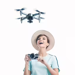 woman in hat looking at the camera and taking a photo with remote control plane flying overhead