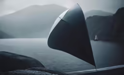 an umbrella sticking out of the rocks by water