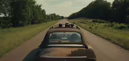 a car driving down the road with two men looking at it