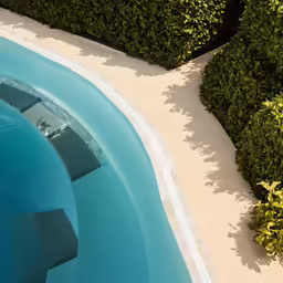 this swimming pool is designed with concrete pavers