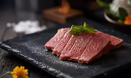 a piece of meat is displayed on a black plate