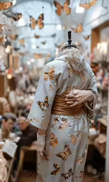 a woman wearing a butterfly print robe standing in front of a store with lots of people