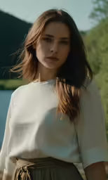 a young woman in a white shirt and a skirt standing near the lake