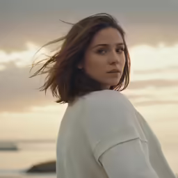 the woman is posing in front of the ocean