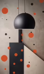 black pendant lamp hangs over a square block of paint with orange dots on it