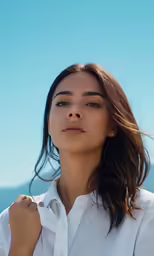 a woman in a white shirt with water behind her