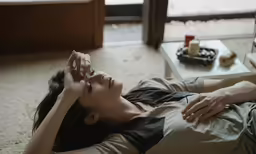the woman is lying down while she is on her cell phone