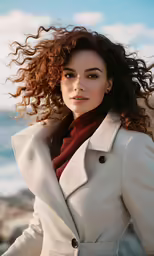 a woman wearing a coat and red scarf near the ocean