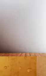 an orange vase with bubbles sitting on top of a wooden table