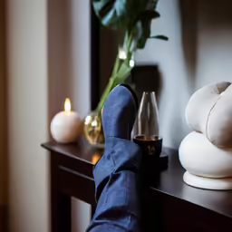 the feet are on the table next to a vase