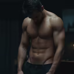 a man standing in a dark room looking down at his torso