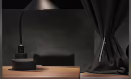 a black lamp sits in the corner on a wooden shelf next to a table