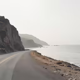 a empty road next to the ocean and cliffs