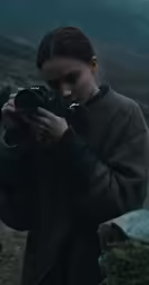 a woman taking a picture with her camera in front of mountains