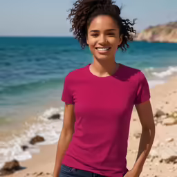 a beautiful woman posing on the beach in a bright pink shirt