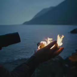 a hand holding something on top of a lake