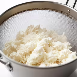 cream in a saucepan, with a strainer