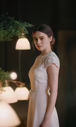 a woman standing next to a tree wearing a white dress