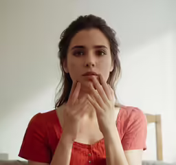 a woman who is staring ahead while she has her hands in her mouth