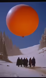 a large orange balloon being lifted from the sky