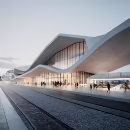 a very long building with a curved roof next to tracks