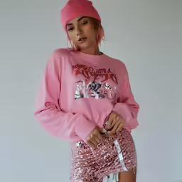 woman in pink sweatshirt and sequin shorts standing