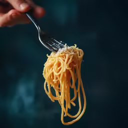 someone is holding a fork full of noodles