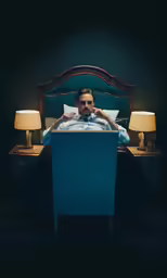 a man sitting in bed with a white and blue headboard