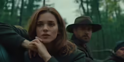 a woman in a hat sits with a man on the other side